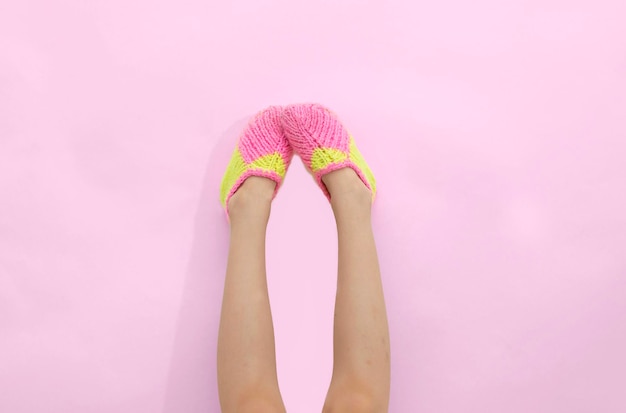 Strana giornata dei calzini. i piedi dei bambini in calzini a maglia multicolori su sfondo rosa. layout, luogo da copiare.