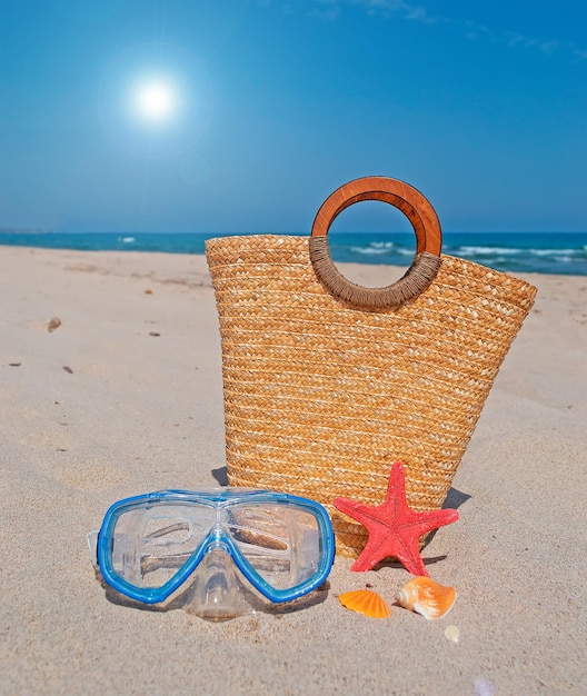 Straw bag diving mask and starfish on the beach