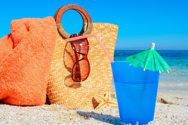 Straw bag and drink by the shore