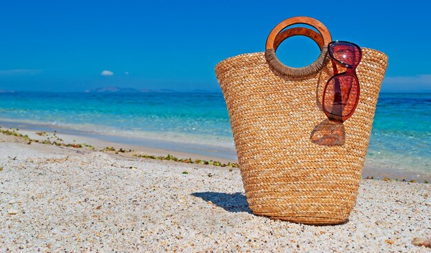 Straw bag and sunglasses by the sea