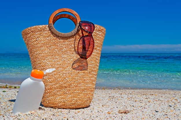 Straw bag and suntan lotion on a sunny shore