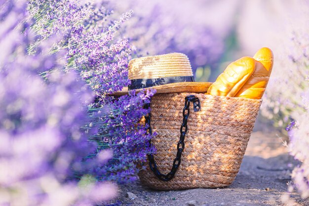 Straw bag with lavender bunch in lavender field with straw hat