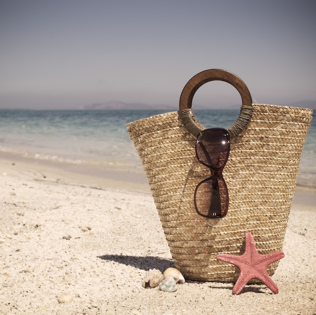 Straw bag with sunglasses and starfish in vintage tone