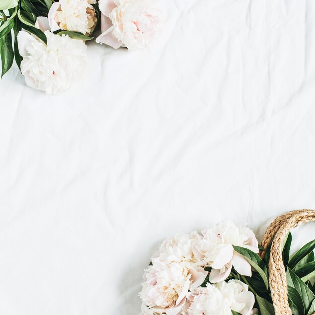 Photo straw bag with white peony flowers on white surface