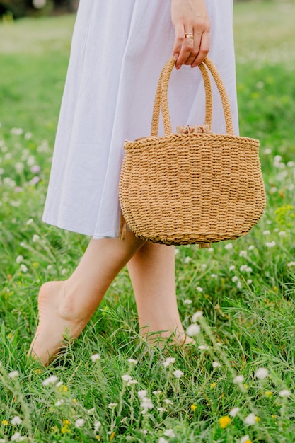 A straw bag with a white ribbon in her hands