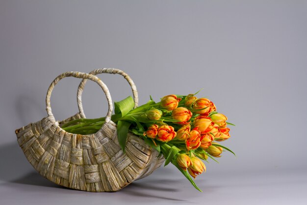 Straw basket with bouquet of fresh orange tulips