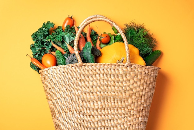 トレンディな黄色の背景に有機野菜とストロー バスケット健康食品ベジタリアン ダイエット環境にやさしい廃棄物ゼロ プラスチック無料コンセプト