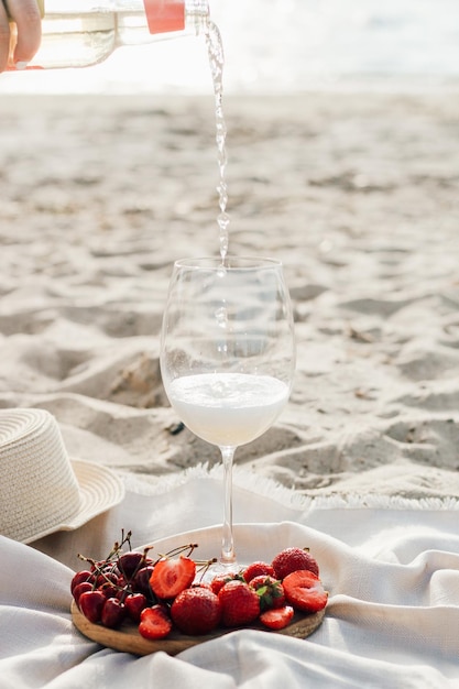 과일과 와인 한 접시와 함께 태양 보호를 위한 챙이 있는 밀짚 해변 모자
