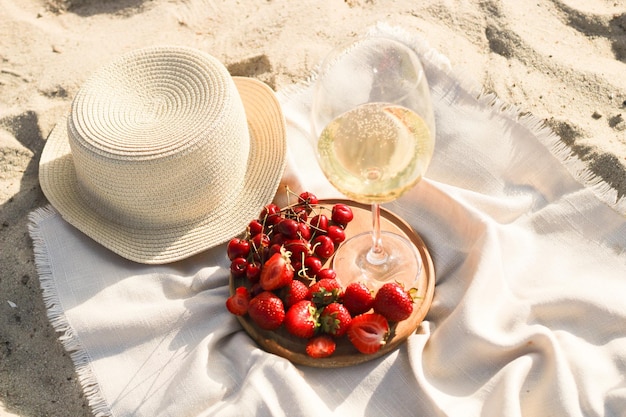 Straw beach hat with brim for sun protection with a plate of fruit and wine