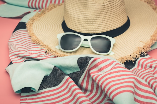 Straw beach sunhat and sun glasses on punchy pink. 