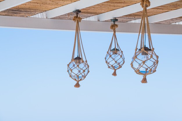 Straw cover the roof of a seaside terrace with hanging lantern.