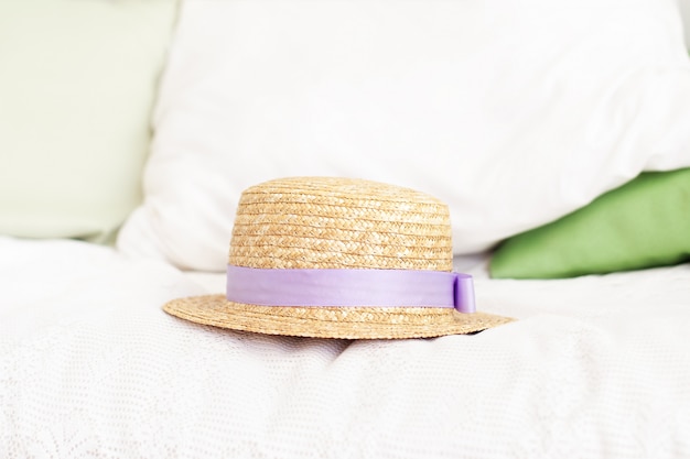 straw hat on the bed. Summer weekend concept. Leisure, weekend, trip. Woman accessories from above. travel or vacation concept. Provence, rustic style. The woman hat on the pillow in bedroom.