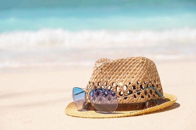 Straw hat and blue sunglasses on seaside shore with blue sea