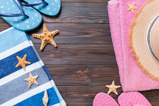 Straw hat, flip flops, towel, sunglasses and starfish On a dark wooden background. top view summer holiday concept with copy space.