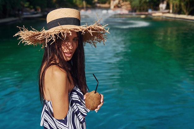 В соломенной шляпе Девушка развлекается и отдыхает в бассейне в дневное время Концепция отпуска