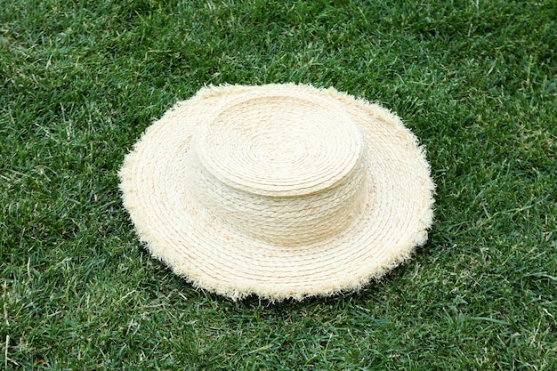 Straw hat on green grass outdoor in summer day