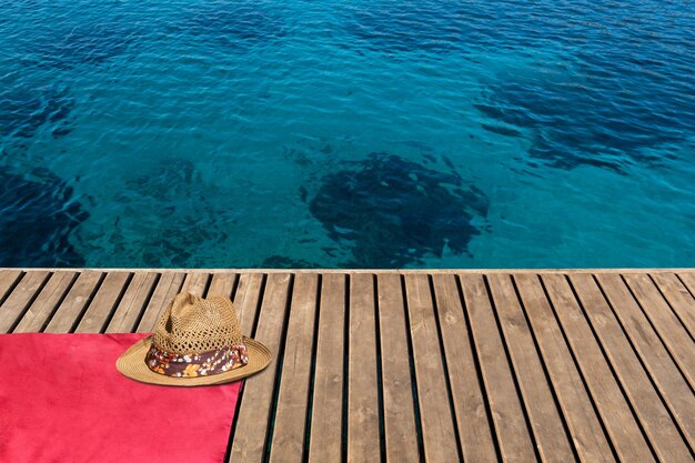 Straw hat standing on red beach towel