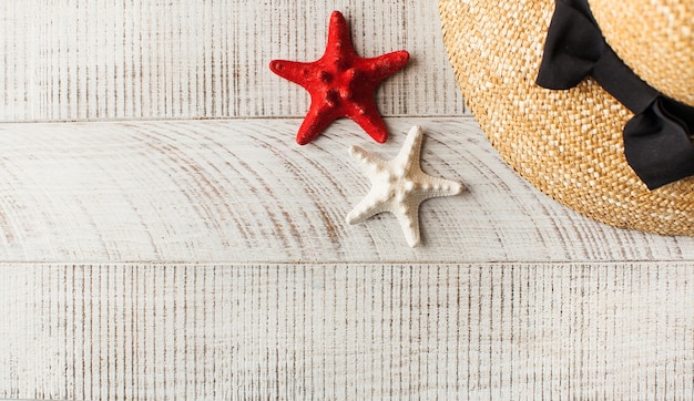 A straw hat and a starfish on light wooden table