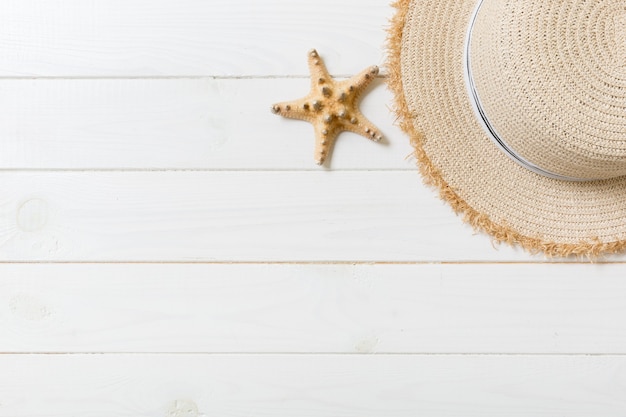 Cappello di paglia e stelle marine su un fondo di legno bianco. vista dall'alto concetto di vacanza estiva con spazio di copia.