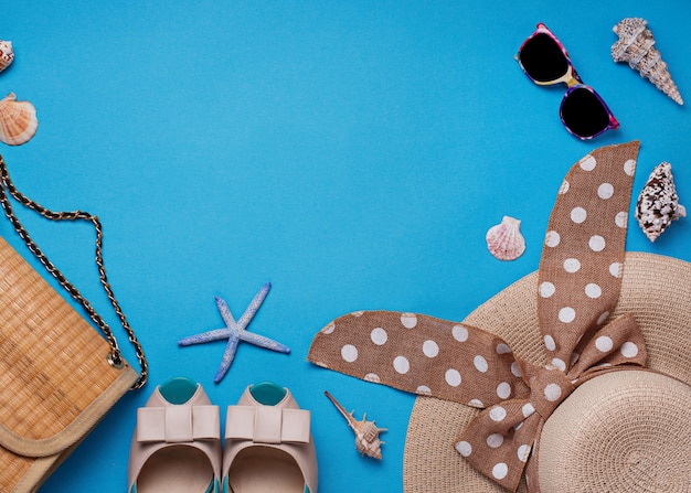 Straw hat, sunglasses and shoes on blue background