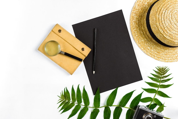 Straw hat with green leaves and old camera on white background Summer background Top view Copy space Still life Flat lay