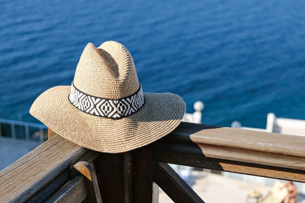 straw hat on wooden terrace  sea and swimming pool view