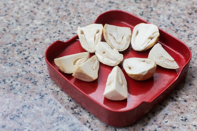 Straw mushrooms in a red tray are placed on a granite table It is an edible and delicious mushroom