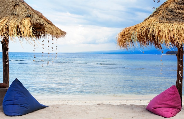 해변에서 밀짚 우산과 콩 가방입니다.
