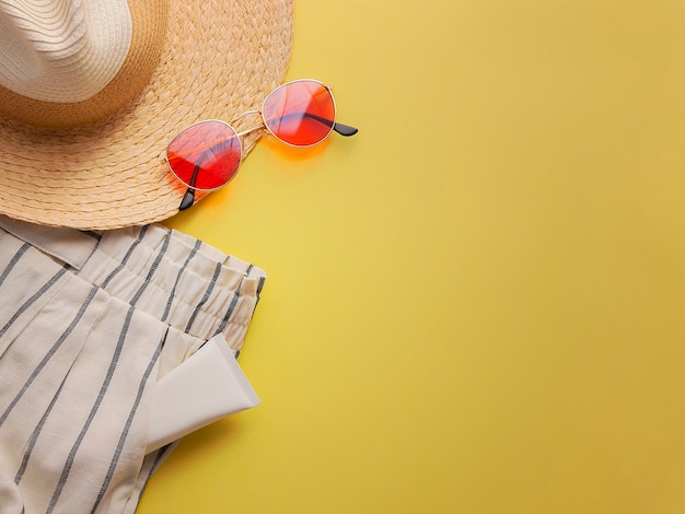 Шляпа соломенной женщины с взгляд сверху солнечных очков и шортов яркой желтой квартиры предпосылки кладет одиночный.
