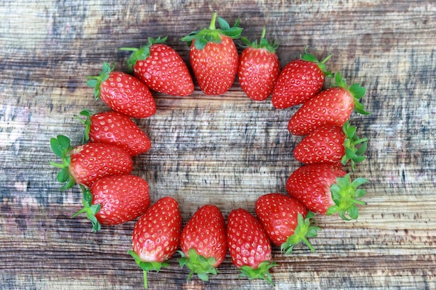 Photo strawberries arranged in a circle on a wooden background