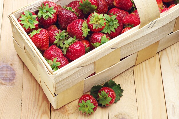 Strawberries in a basket and near on a wooden table