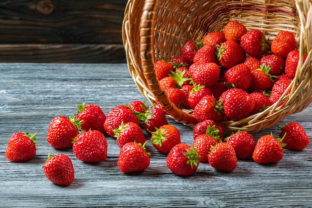 Strawberries in basket on wooden board.