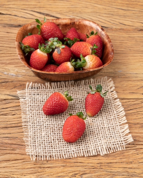 Strawberries in a bowl over wooden table.