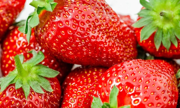 Strawberries in bulk closeup berries with leaves selective focus