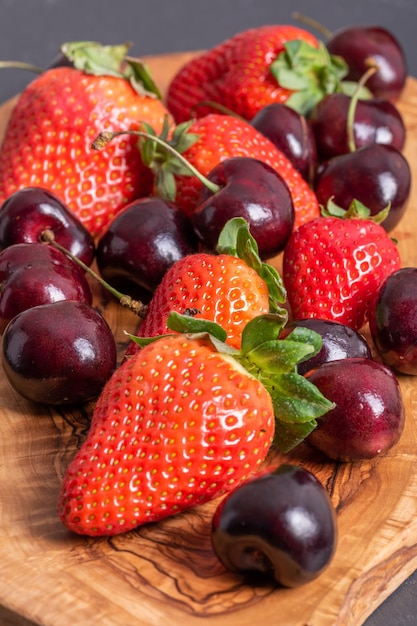 Strawberries and cherries on wooden chopping board