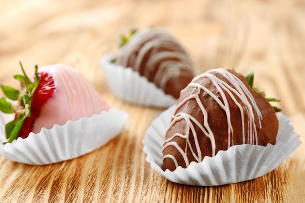 Strawberries in chocolate on wooden surface