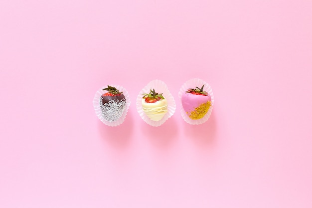 Strawberries covered with chocolate on a pink background.