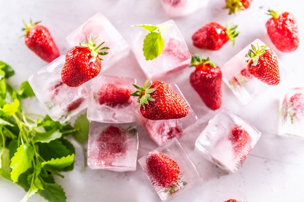 Strawberries frozen in ice cubes with mellisa leaves Top of view