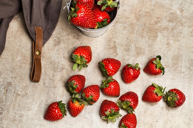 Photo strawberries in a galvanized bucket and on a marble table