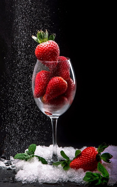 Strawberries in glass on the black wall