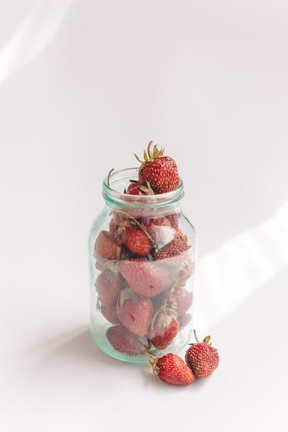 Strawberries in a glass jar. Summer composition, minimal style