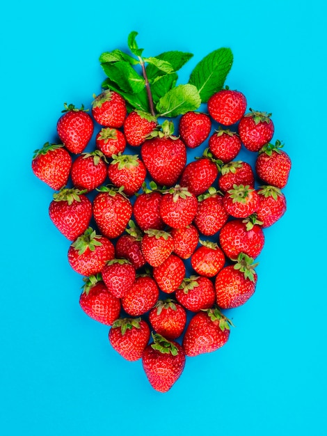 Fragole e foglie di menta su sfondo blu