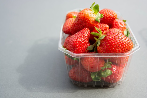 Strawberries in plastic box pack background. Zero waste concept, no plastic