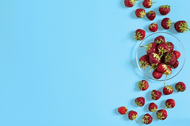 Strawberries in a small plate on the table. Background with ripe fresh strawberries lying in a plate. Top view. Copy space. Flat lay
