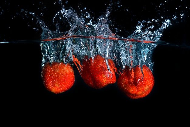 Foto fragole che spruzzano nella spruzzata della chiara acqua