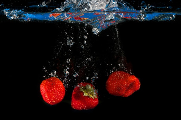 Strawberries splashing into water