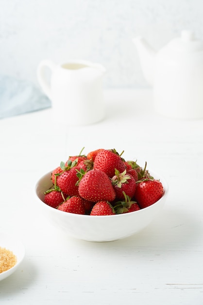 Strawberries in white bowl on white table