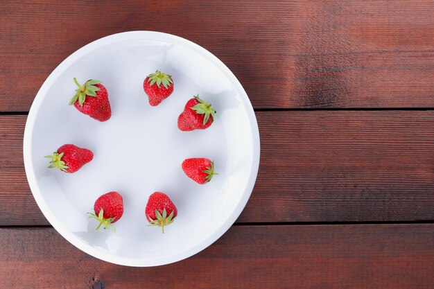 하얀 접시에 딸기 나무 배경 복사 공간에 빨간 딸기