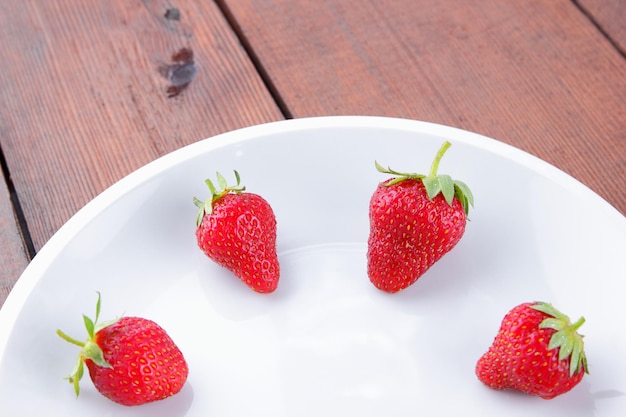 Strawberries on white plate Red strawberries on wooden background Copy space