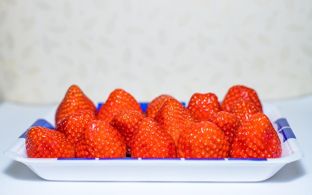 Strawberries in a white plate on a white table Selective focus